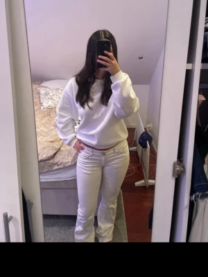 Vita bootcut jeans från Nelly - Säljer ett par vita bootcut jeans från Nelly med snygga kontrastsömmar och dubbla knappar i midjan. Jeansen har  bakfickor med broderad detalj.