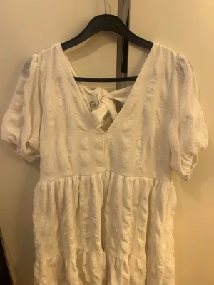 Vit kortklänning från Bubbleroom - Supersöt vit kortklänning med snygg knytning i ryggen. Perfekt för student eller till sommarn🩷 Använd en gång av en tidigare användare