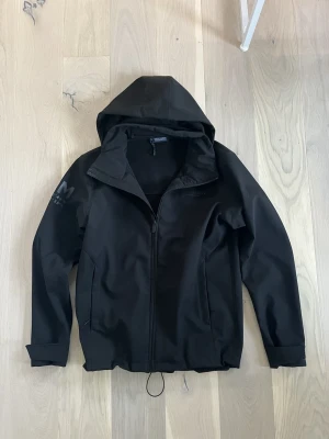 Svart vindjacka från Race Marine - Säljer en svart vindjacka från Race Marine i storlek M. Jackan har huva, dragkedja framtill och två sidofickor. Materialet är slätt och känns sportigt, perfekt för blåsiga dagar. Enkel och stilren design med diskret logga på ärmen.