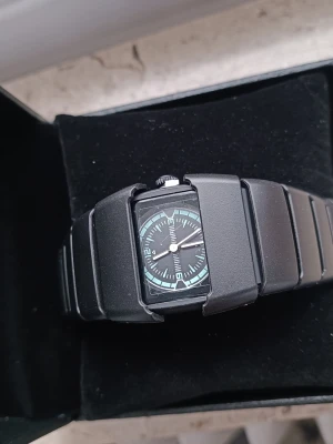 Futuristisk Mattsvart Klocka - Säljer en stenhård klocka i mattsvart finish med en unik, futuristisk design.  Design: "Stealth"-look med svarta detaljer och snygga cyan-blå visare/markeringar som sticker ut. Skick: Helt ny och oanvänd i originalbox. Stil: Perfekt för dig som gillar techwear, street eller gorpcore-stilen. En klocka som verkligen ger karaktär åt din outfit utan att vara skrikig.