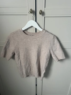 Beige stickad kortärmad tröja H&M XS - Supermjuk och basic beige stickad tröja från H&M i storlek XS. Tröjan har korta ärmar, rund halsringning och ribbade kanter.