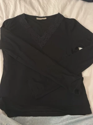 långärmad topp med spets - Säljer en svart långärmad topp från Gina Tricot i storlek 158/164. Toppen har en snygg v-ringning med bred spetskant som ger en extra detalj. Materialet är mjukt och stretchigt, perfekt till många olika looks.