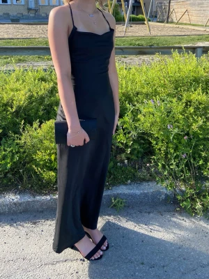 Svart bal med snörning - Supersnygg svart balklänning med tunna axelband och öppen rygg med snörningsdetaljer. Är från oh polly men köpt här på Plick. Ändast använd en gång men säljer för den är förliten och kommer inte till användning längre. 