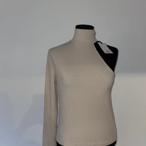Topp med en arm - Beige topp från Bikbok med hög hals. Strl M. Helt ny med lapp kvar 