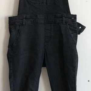 Black jean overall - Black jean overal. Long skinny pants. Closing with bottons on the left side. Pocket on the chest and 4 on the pants.