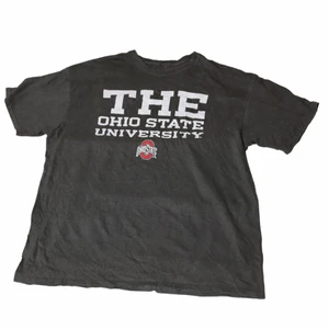 The Ohio State University- Vintage Tee - En sjukt Nice mörkgrå tröja som är från ett stort college i USA. Har ett fett tryck som är över nästan hela framsidan och ger lite kontrast. Är perfekt för dig som gillar late 90’s college viben. Ha den som oversized för full effekt! Thriftad i Ohio.