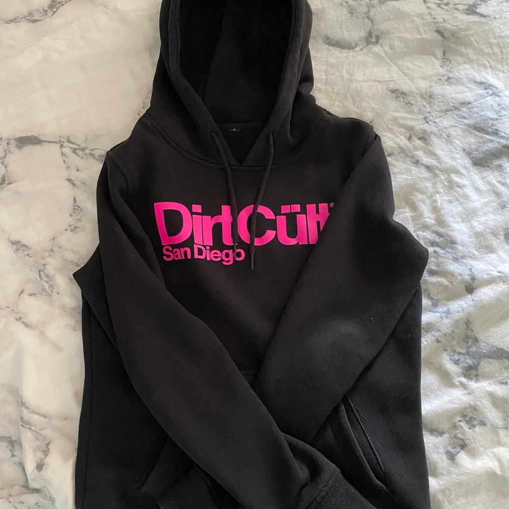 En svart och rosa nästintill oanvänd DirtCült hoodie. Den är i fint skick, färgen är fortfarande mörk svart och ej något urtvättad. Trycket är även som nytt. Den är ganska liten i storleken så även fast det står S så skulle jag nog säga att den passar bäst till XS då den annars är lite tajt. . Hoodies.
