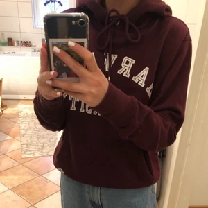 Huvtröja  - En mysig huvtröja som är vinröd 🥰 säljes för att den inte kommer till användning.                                      (Dock är den är lite sliten vid texten)