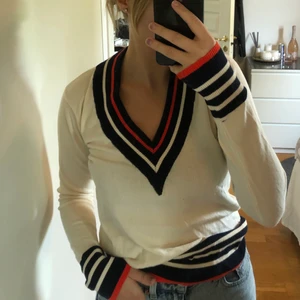 Vit stickad med det lilla extra - En vit stickad tröja med V-ringning samt ränder i blått, vitt och oranget. Otroligt skön och enkel men samtidigt lite extra. Storlek Xs men passar XS-M beroende på.