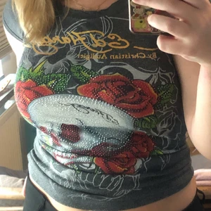 ed hardy tisha - så snygg o smickrande ed hardy tröja!! i bra skick med endast några saknade rhinestones, o snyggt tryck. i stretchigt material, men skulle gissa att det är ungefär en M?