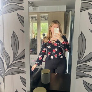 Blommig blus med knytning  - Söt blus fylld med rosor, har även knytning framför brösten. Tunnt och härligt tyg och i väldigt fint skick. Storlek S. Spårbar frakt på 66kr tillkommer:)