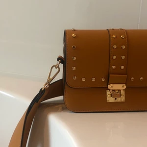 Väska i senapsgul färg - En väska från Lindex. Färgen är en mörk nyans av gul. Den är smyckad med guldiga knappar och detaljer. Använd väldigt sällan och försiktigt. Väskan är i samma STORLEK som en vanlig handväska (lite mer än 15 cm) PRIS I AFFÄR ligger på 249 kr. Säljer pågrund av att jag sällan använder den👜👜👜