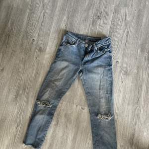 Blåa jeans med hål som är avklippta och passar en person som är cirka 155-160