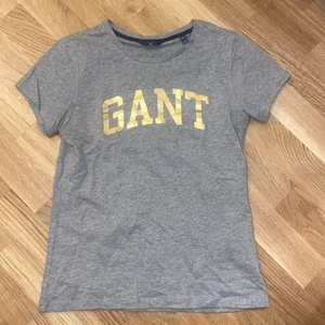 GANT T-shirt  - Grå T-shirt från GANT med guldigt tryck. Storlek XS. Knappt använd!