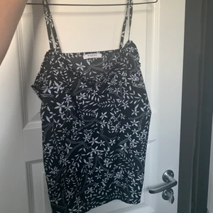 Mönstrat svart vitt linne storlek S  - Mönstrat linne med blommor. Vit /vitt och svart färg. Från Pieces. Storlek S /small.  Fina detaljer vid bysten och ut under ärmarna. (Se bild). Reglerbara axelband. Mycket bra skick! Frakt tillkommer.