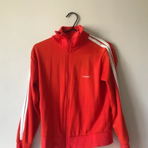 Svin cool tjocktröja köpt i USA - Säljer en jätteskön vintage tjocktröja med krage. Den är röd orange och har två streck på ärmarna😇 Jag har själv köpt den i en secondhandbutik när jag var i USA. Det är därför jag inte vet var den kommer ifrån. Säljer pga att jag ej använder och för att den är lite stor då jag är storlek S och denna skulle jag säga är mer åt M👌🏼 Hoppas nu att någon vill köpa!