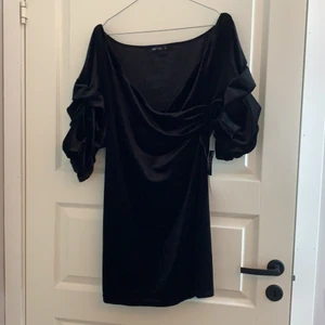 Sammetsklänning - Svart oanvänd offshoulder sammetsklänning med prislapp kvar. Saknas ett snöre som man kan sätta runt midjan (se bild 2) men går att styla med ett snyggt skärp eller ingenting. Den har ”ihopskrynklade” armar och sitter tight på kroppen nedtill.