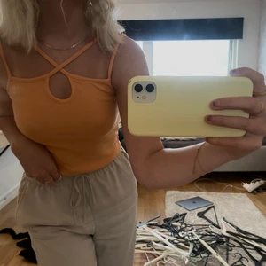 Oragne linne storlek XS - Ett oragne linne med korsade band. Linnet är använt 1 gång och är i storlek XS. Ordinarie pris 120kr