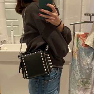 Väska med nitar - INTRESSEKOLL på denna väska, säljer för bra bud! Väskan är från Zara och är slutsåld och kommer förmodligen inte tillbaka. Har en defekt då ena dragkedjan låstnat men inget som man tänker på eller som påverkar så mkt