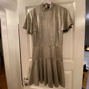 Guldglittrig klänning - Säljer denna festliga guldglittrande klänning från Nelly. Köpt för ett år sen och använd en gång så den är i mycket fint skick💗 perfekt nu till nyår☺️