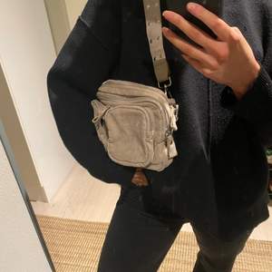 Grå väska i mocha material! Jätte söt och rymmer mycket! Följer även med ett band till så man kan ha den som en crossbody!🥰💘🤙🏼