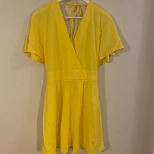 Gul klänning - Oppenrygg och sitter åt i midjan. Snygg passform. Använd endast en gång till ett event, helt felfri