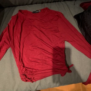 Långärmad topp - Burgundy färg/mörkare röd. Använd en gång, går att göra kortare/längre med snörena på sidan