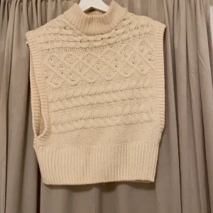 Stickad väst - En fin stickad väst med stickade detaljer på både fram och baksidan. Stora öppningar på sidan. Men tyvärr ett litet hål på ena sidan som man kan sy ihop lätt där av priset