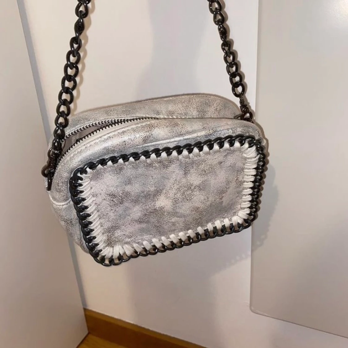 VIT/SILVRIG AXELREMSVÄSKA MED GRÅTT KEDJEBAND.