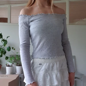 Grå off-shoulder topp från Brandy Melville - Grå off-shoulder topp från Brandy Melville i storlek "one size" men uppskattningsvis passar den XS-M. Den har fina volanger (ruffles) vid "kanterna" av tröjan. Frakt tillkommer men kolla gärna in mina andra annonser för samfrakt!💞