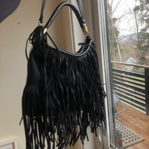 Svart väska - Svart väska med svart fringe. Kommer med två axelband, ett länge och ett kortare