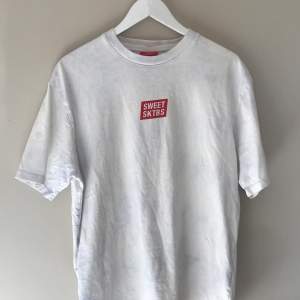 sweet skbs t-shirt i vit med lila/blå inslag köpt från junkyard. Bra skick!