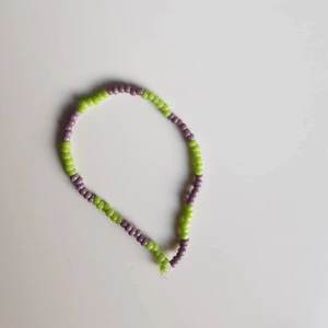 Lila och grönt pärlarmband  - Handgjort pärlarmband. Precis som på alla andra smycke går det fint att önska vilka färger man vill ha eller inte vill ha med.