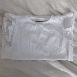 Tröja med volanger - Säljer denna helt oanvända jätte fina vita t-shirten med små blommiga volanger, har tyvärr inte prislappen kvar men har bara provat den. Storleken är 158-164 som är ungefär xs/s. Kommer inte ihåg nypriset men tror de va 150kr och jag säljer den för 100kr. Kontakta mig vid intresse!💖 Köparen står för frakten.