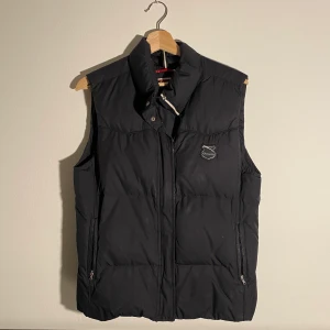 Champion dunväst  - Superhärlig dunväst från champion som inte kommer till användning. Lite skavt på märket med annars bra skick. Passar XS-L beroende på fit. Bra att dra på över en tjock stickad eller köra som extralager under vinterjackan! Köpare står för frakt.