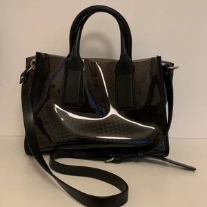 Handväska från Zara - Handväska som även funkar som axelbandsväska från Zara. Väskan är i fake läder och plast. Tillhörande tyg ”necessär” kommer med. Botten på väskan är 29x13 cm och 21 cm hög. Nyskick. 