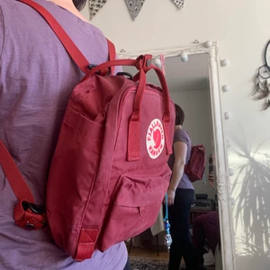 Kånken mini ryggsäck  - Säljer nu min älskade mini Kånken. Använd varsamt, nästan som ny!! Jätte fin mörkröd färg. Smycket som hänger på den kan jag ta bort :) 