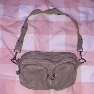 !!!GRATIS FRAKT PGA SKADA!!! - En fin beige väska med 4 fack från Gina tricot! Använd ganska mycket och har därför en liten skada längs bandet och en pytte liten skada på en av framfickorna tyvärr. Den är väldigt rymlig och har fina silverdetaljer längs med bandet!