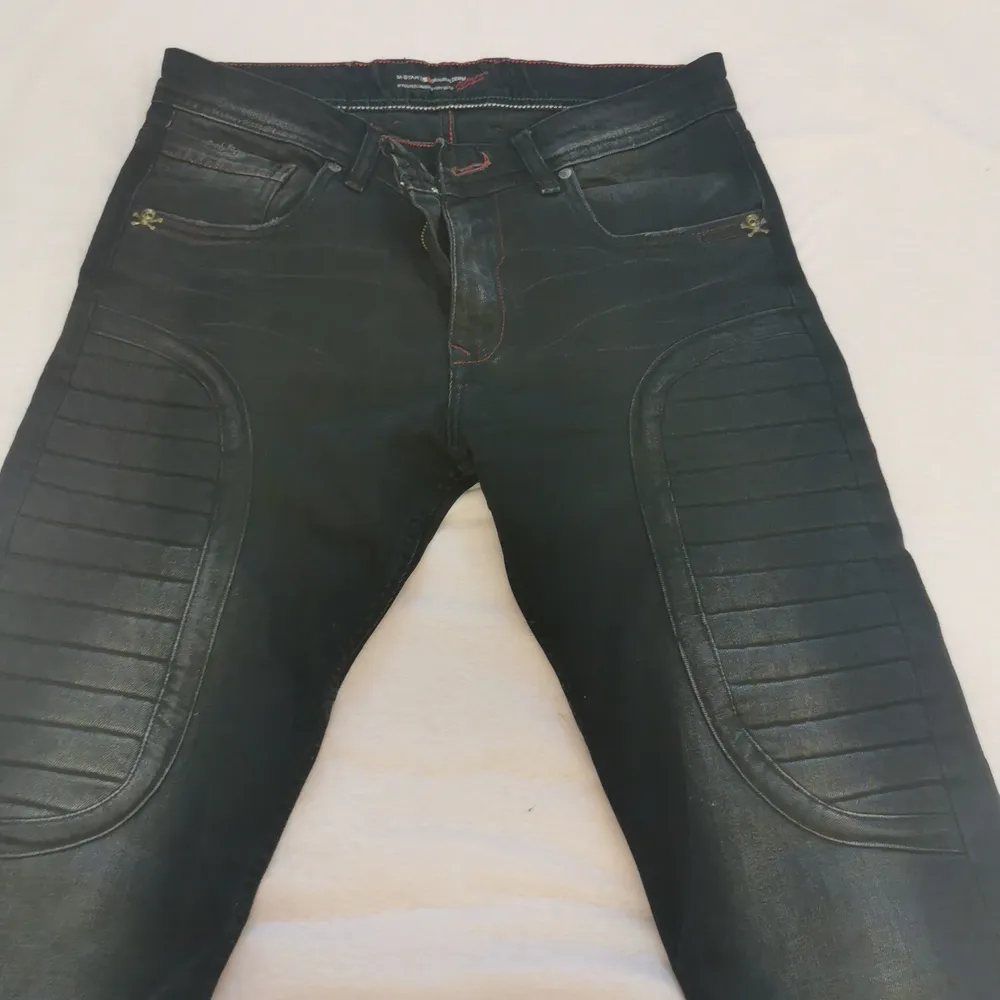 Dessa svarta jeans har en skalle på båda av de främre fickorna och dessa skallar är målade i färgen guld. Jeansen har också en tjockare material precis ovanför knäna som ni kan se på bilden. De köptes för 3 år sedan man har inte används på nästan två år. Jeans & Byxor.