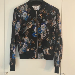 Blommig tunn jacka - Jacka i blusmaterial med tjockare material i ärmar och midja. I mycket gott skick, använd endast några fåtal gånger. Passar bra på mig som är 177cm. 