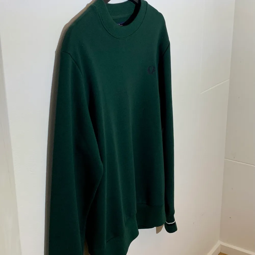 Nyskick Fred Perry sweatshirt i mörkgrönt. Prövad 1-2 gånger. Inga fläckar eller skador samt aldrig tvättad. Bomull och polyester. Nypris 1100kr.. Tröjor & Koftor.