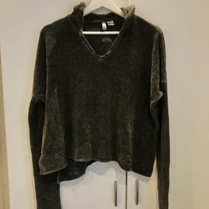 Stickad med luva - Jättefin grå stickad tröja i smått kort modell i midjan. Har luva och hål i ärmarna för tummarna. Jättemysig :) Använd ett fåtal gånger bara.