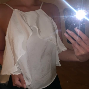 Vit topp - Ett vitt linne i blusmaterial med volanger framtill. Säljer den då den blivit lite liten för mig. Den är i storlek xxs (men har passat bra på mig som varit en xs/s). Köpare står för frakten om så önskas. Skriv till mig på dm💖