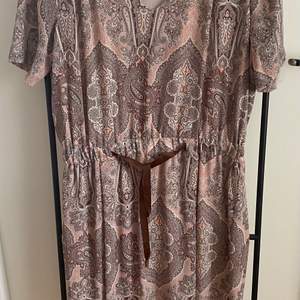 Storlek 40 Paisleymönstrad klänning i puderrosa/gråbrun färg Tunn och härlig med foder och litet skärp i midjan Jättefint skick