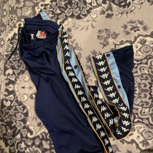 Kappa - Byxor ifrån kappa marinblå, babyblå på sidorna.  Knappar på sidorna av bena. En UNISEX BYXA frakt ingår i priset 