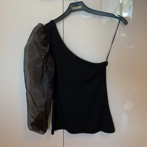 Svart topp med en puffärm från Ginatricot  - Svart topp med en puffärm från Ginatricot. Storlek 38. Använt endast en gång.