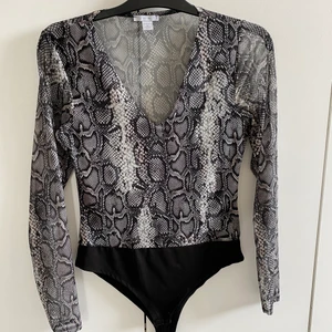 Body i ormmönster - Snygg långärmad body i ormmönster. Ärmarna är transparenta men inte resten. Köparen står för frakt. 
