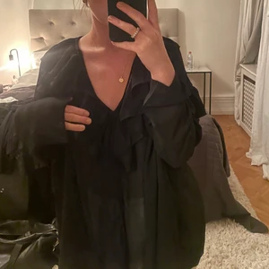 Svart blus  - Romantisk svart blus med fina volanger. Den är lite genomskinlig. Den är ganska stor i storleken 