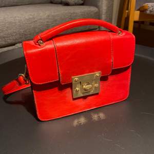 En röd liten handväska som passar perfekt till att göra en vanlig outfit lite coolare köpt på Lindex