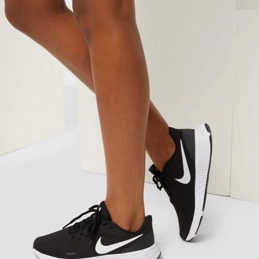 Sportiga sneakers från Nike. Svarta med vita detaljer och en mörkgrå reflex. Skorna har inga skador, men är smutsiga på det vita gummit. Storlek 40, eller 24,5 cm innerlängd.. Skor.